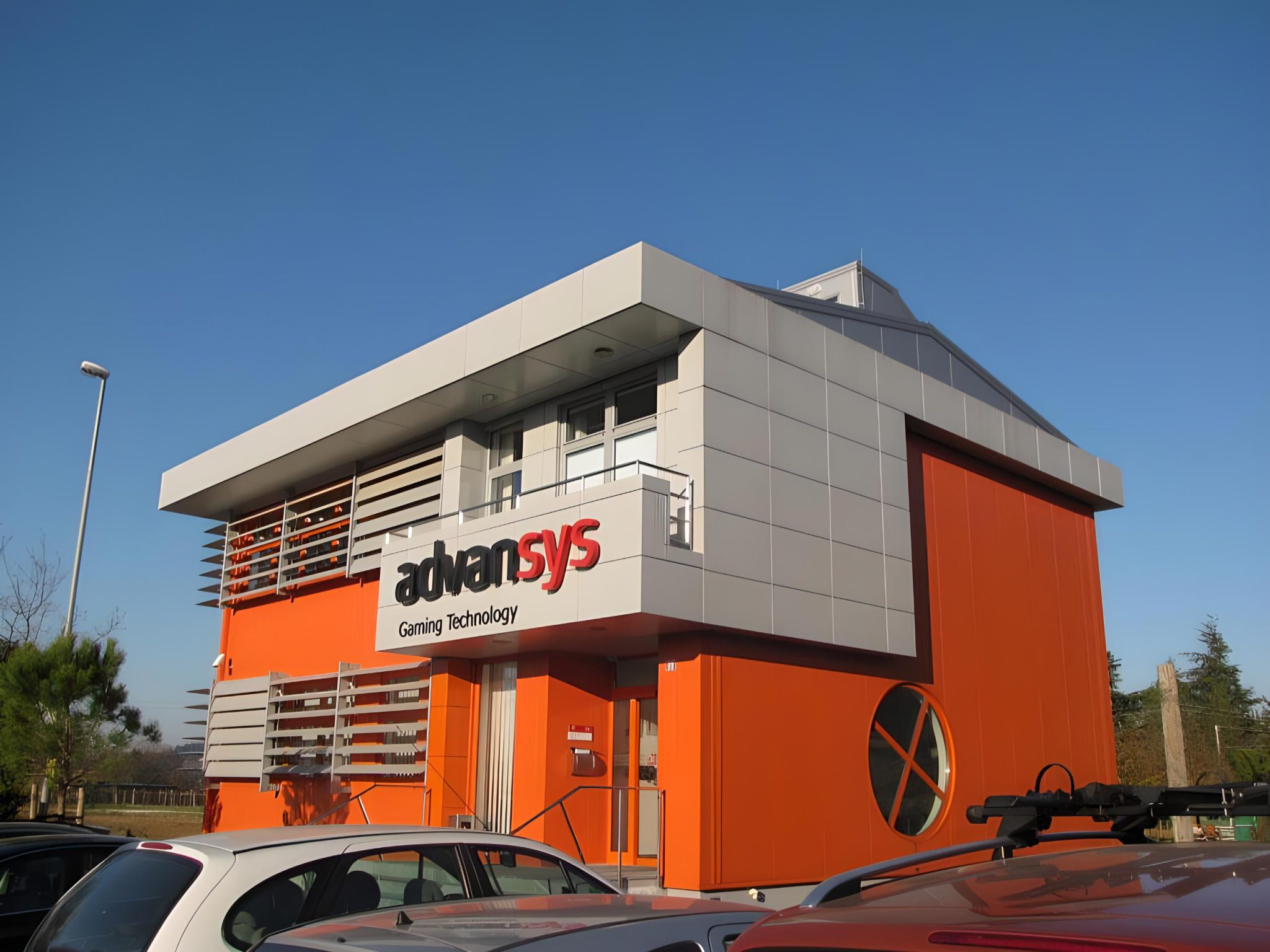 Zunanjost poslovno-proizvodnega objekta Advansys v Solkanu z modernim oranžno-srebrnim ovojem.