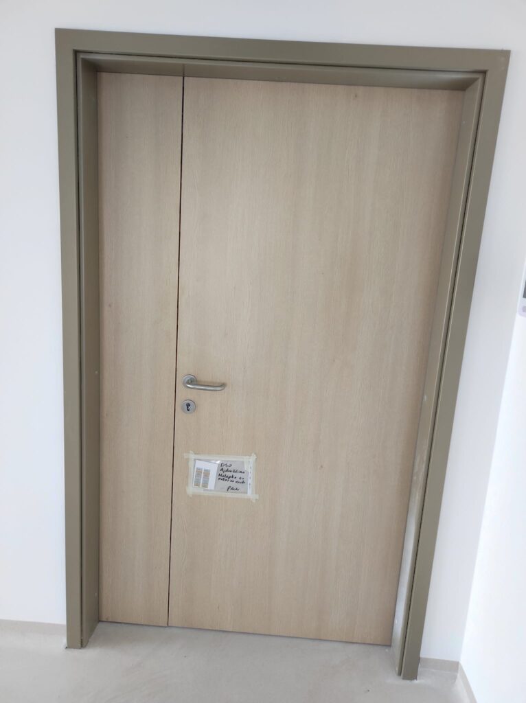 Zaprta protipožarna vrata z inox ročajem in deklaracijsko nalepko po vgradnji.