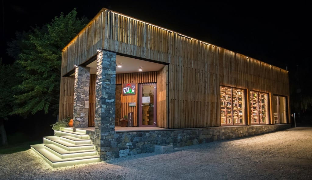 Nočni pogled na Kamp Lijak z osvetljenimi lesenimi lamelami in integrirano LED razsvetljavo.